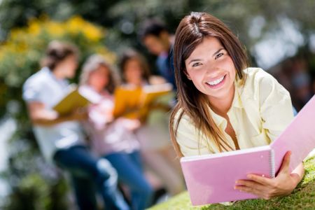 Beautiful college girl studying outdoors and looking happy