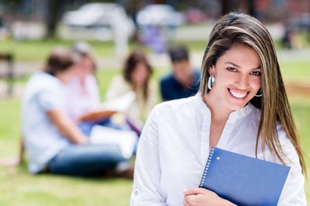 Casual student smiling outdoors with a group at the background 