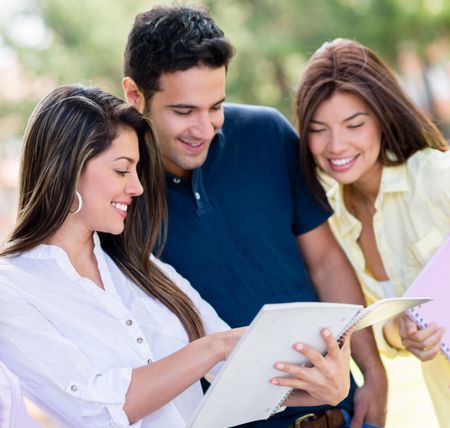Group of friends studying together outdoors looking happy 