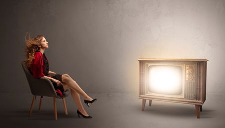 Elegant young lady watching to a vintage television