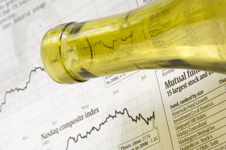Neck of wine bottle above financial page of newspaper