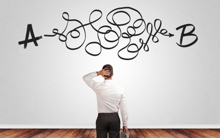 Businessman looking for connection between two things while standing in front of a wall