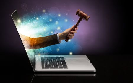 Hand with hammer coming out of a laptop with sparkling effects