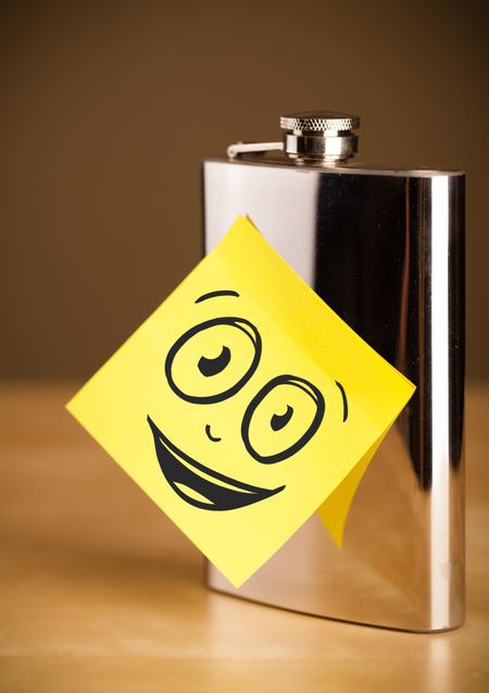 Drawn smiling face on a post-it note sticked on a hip flask