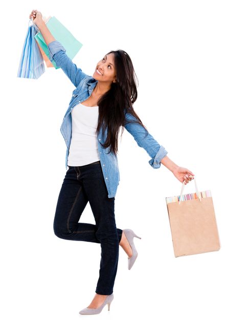 Happy shopping woman with arms up holding bags - isolated over white 