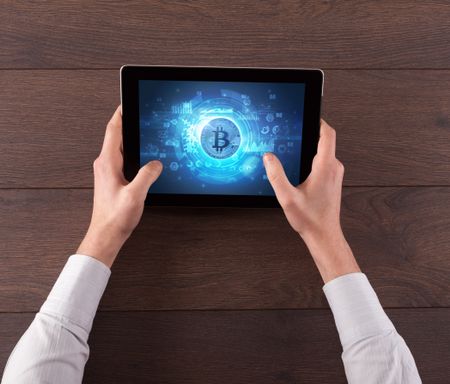 Hand working on tablet with cryptocurrency and network concept
