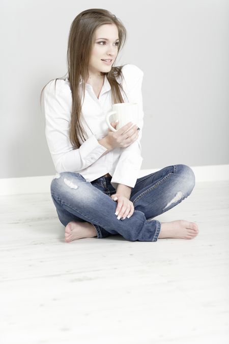 Beautiful young woman relaxing at home with a coffee