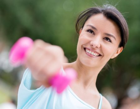 Happy woman portrait training outdoors with free weights 