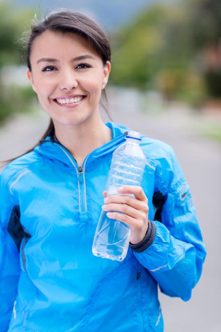 Fit woman outdoors holding a bottle of water 