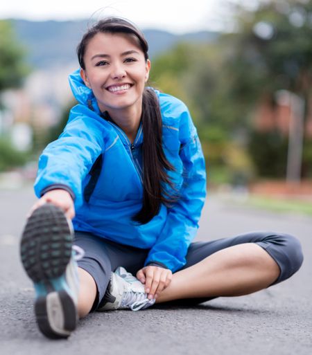Athletic woman stretching outdoors and looking happy 