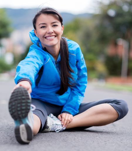 Athletic woman stretching outdoors and looking happy