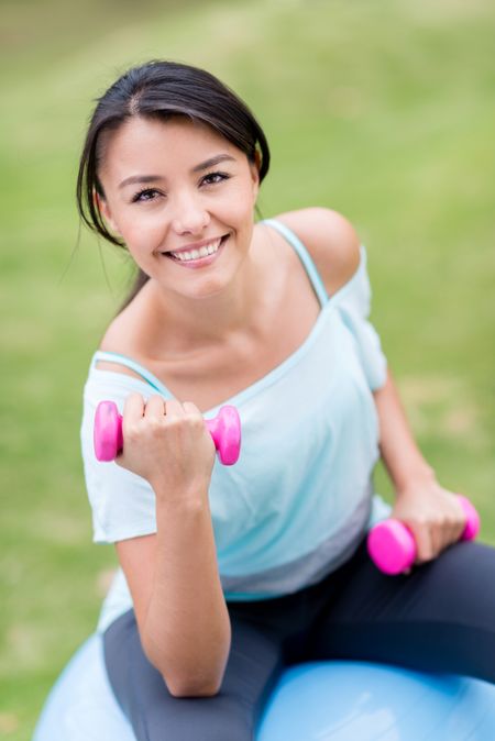 Woman exercising outdoors with a Pilates ball 