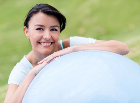 Happy woman doing Pilates outdoors with a fitness ball 