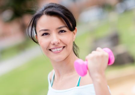 Portrait of a fit woman lifting weights outdoors 