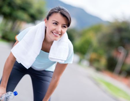 Fit woman resting while running in the city and smiling 