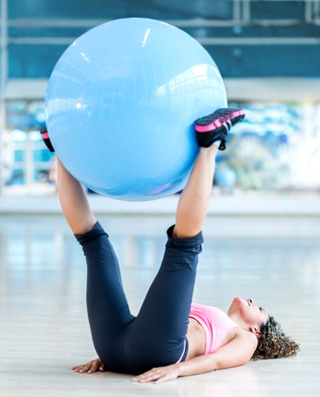 Fit woman exercising with a Swiss ball at the gym