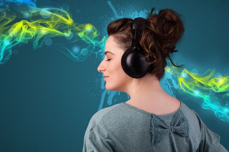 Pretty young woman with headphones listening to music, glowing smoke concept
