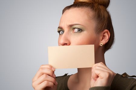 Cute girl holding white card at front of her lips with copy space on gradient background