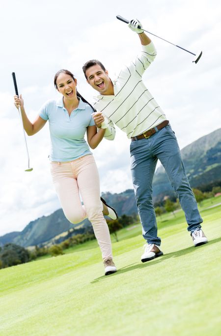 Couple playing golf looking very happy with arms up 