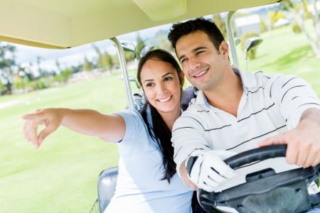 Happy couple at the golf course driving a cart 