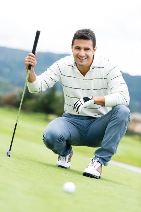Male golf player at the course holding a club 