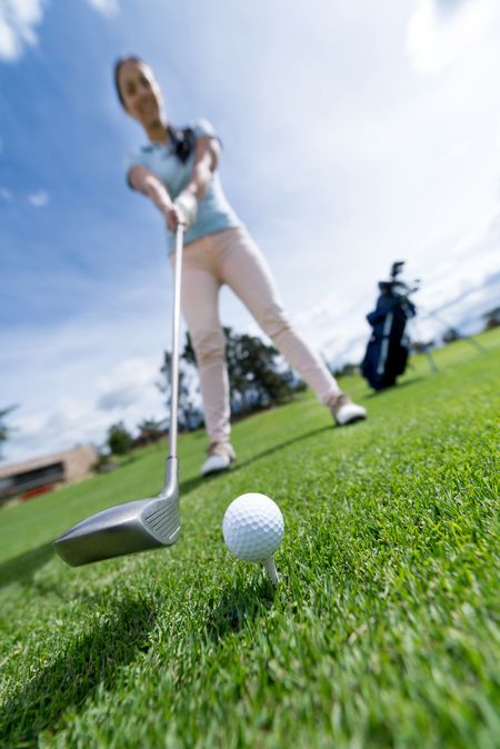 Woman playing golf at the course - focus on ball 