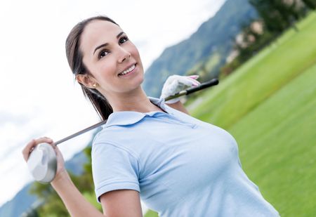 Female golf player at the course holding a club 