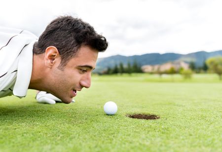 Golf player blowing the ball into a hole 