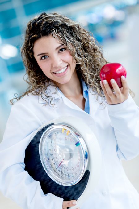 Nutritionist holding a weight scale and an apple - healthy lifestyle 