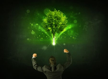Young businessman standing with a glowing tree and letters above his head