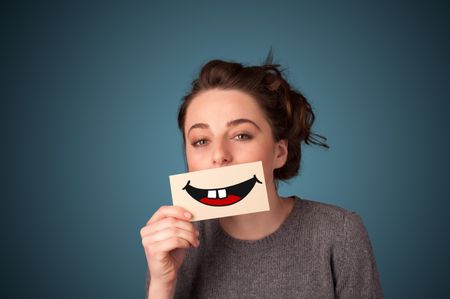 Happy pretty woman holding card with funny smiley on gradient background