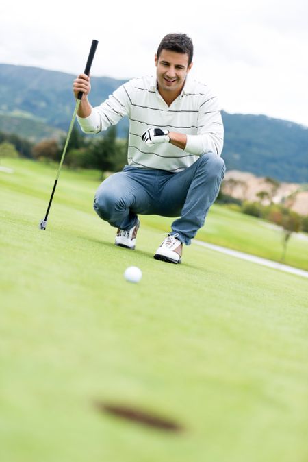 Man playing golf looking at the ball going into a hole 