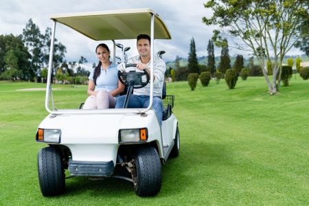 Couple in a golf cart at the course looking very happy
