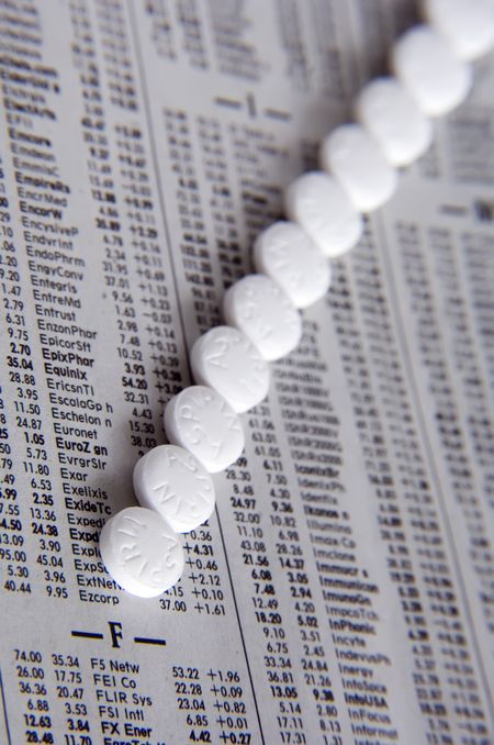 Row of aspirin on page of daily stock report