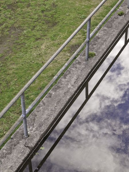Optical illusion after rain: Fence between grass and reflective puddle at historical gun battery at Fort Stevens, Oregon