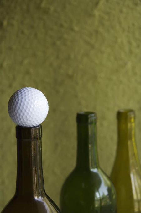 Golf ball on mouth of wine bottle (focus on golf ball in foreground)