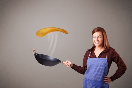 Beautiful young woman making pancakes