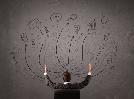 Young businessman sitting and deciding in front of a chalkboard with sketched arrows and signs in different directions