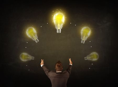 Young businessman thinking in front of a blackboard with glowing lightbulbs over his head