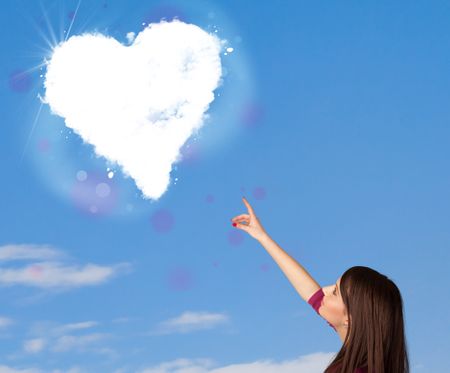 Cute girl looking at white heart cloud on blue sky concept