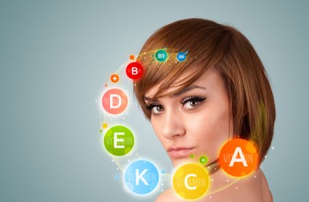 Pretty young girl with colorful vitamin icons and symbols on gradient background