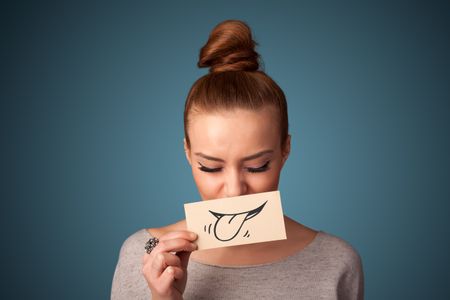 Pretty young girl holding white card with smile drawing on gradient background