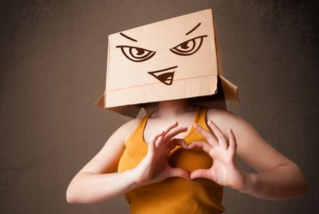 Young woman standing and gesturing with a cardboard box on her head with evil face