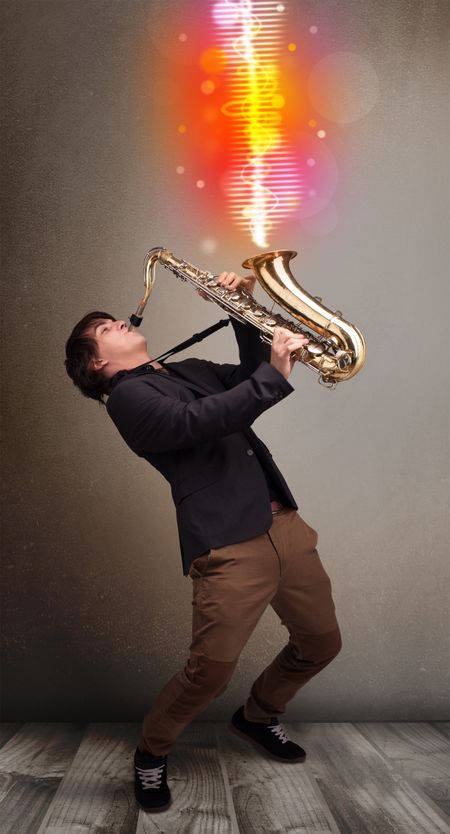 Attractive young man playing on saxophone with colorful sound waves