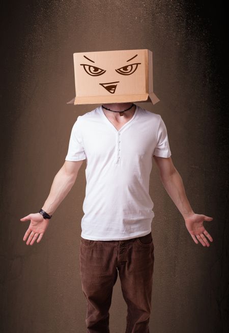 Young man standing and gesturing with a cardboard box on his head with evil face