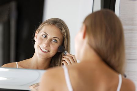 Attractive young woman in underwear applying make up in bathroom.