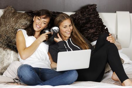Two young women relaxing and listening to music at home