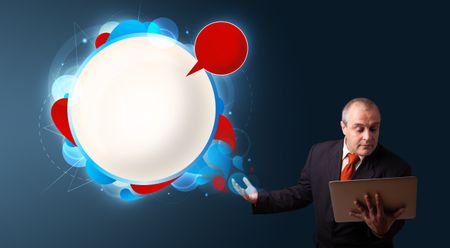 Businessman in suit holding a laptop and presenting abstract modern speech bubble with copy space