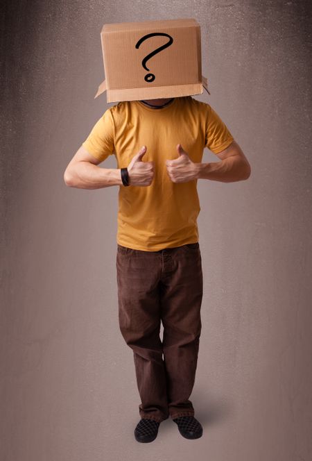 Young man standing and gesturing with a cardboard box on his head with question mark