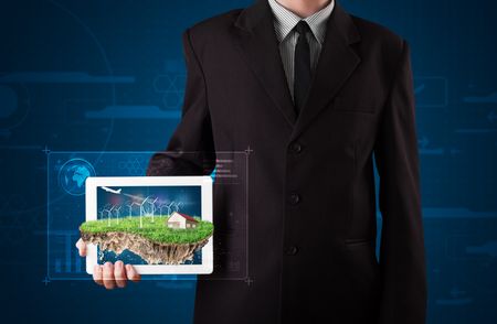 Young businessman presenting a perfect ecology land with a house and windmills